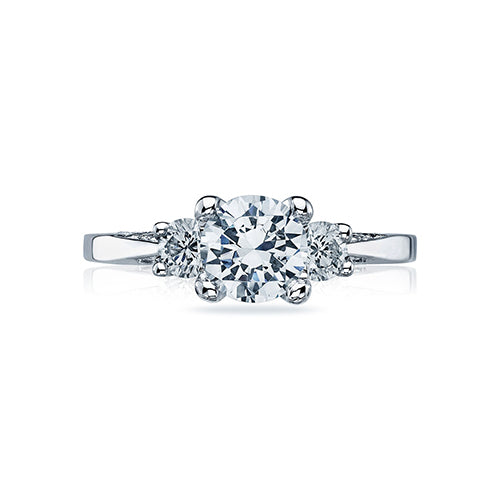 Simplicity and sparkle are the hallmarks of this three stone diamond engagement ring, featuring a round brilliant-cut center stone with a high-polished shank, two round diamond side stones and pave-set diamonds accenting the signature crescent details below the head.