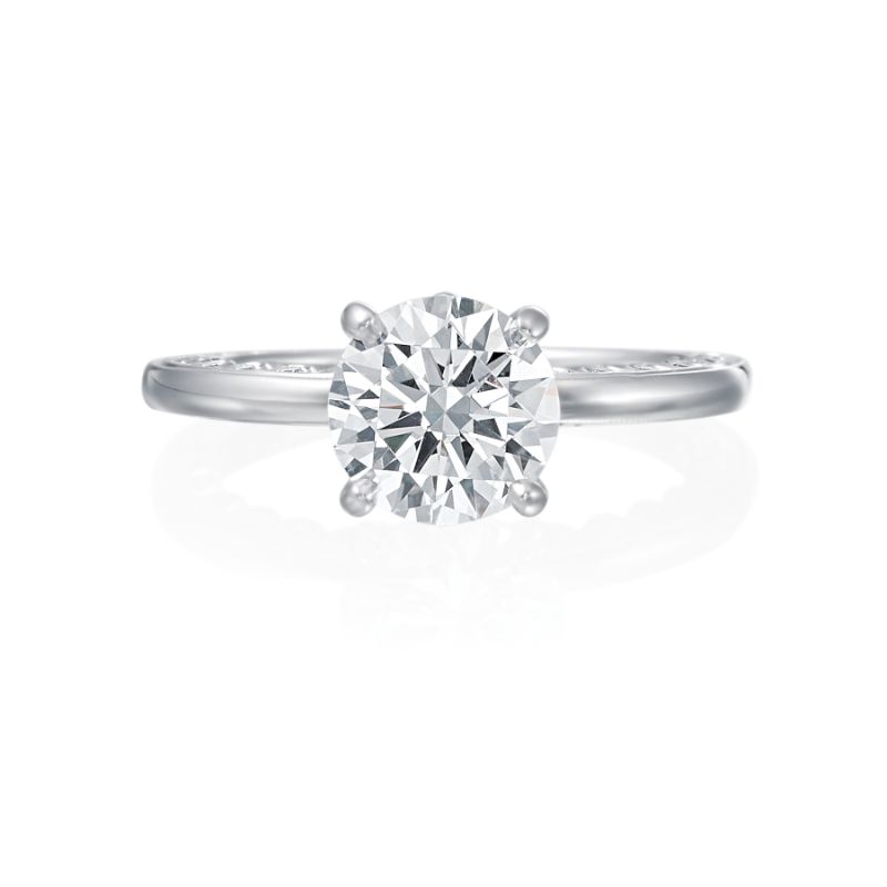 From the top view of this engagement ring, this ring is a simple 18k white gold solitaire. However from the side profile, the wearer can enjoy a row of bezel set diamonds traveling half way around on both sides of the ring. This ring is perfect for the bride who wants a solitaire but delights in the beauty of hidden diamond details. Center diamond is not included in the price shown. 