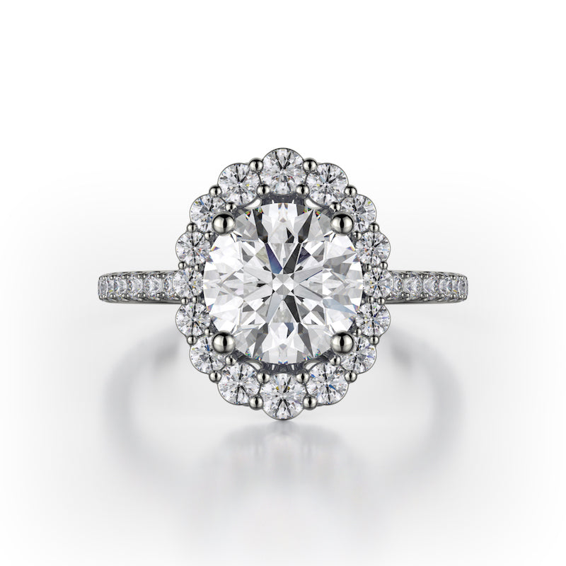The graduated size of the diamonds in the halo of this 18K white gold engagement ring give the ring the appearance of an oval diamond even though the center stone is round brilliant. There are 0.55ctw diamonds in the halo and on the shank of the engagement ring. Those diamonds are G-H in color, SI1-2 in clarity. The metalwork under the head of the engagement ring is exquisite, giving the wearer a beautiful profile to peek at. The center stone is not included in the price. This engagement ring ca